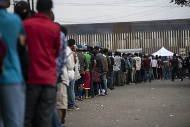 Central American migrants -- mostly from Honduras -- line up for food outside a shelter in Tijuana, Mexico, near the US-Mexico border fence