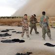 Fighters from the Syrian Democratic Forces (SDF) walk along a road dotted with black veils ditched by women after they crossed over from Islamic State group territory near Tishreen Farms, on the northern outskirts of Raqa on May 2, 2017