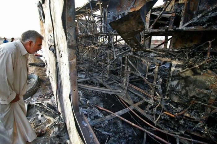 An Iraqi man inspects the wreckage of a bus that was damaged in a car bomb attack, in the southern Iraqi city of Basra on May 20, 2017
