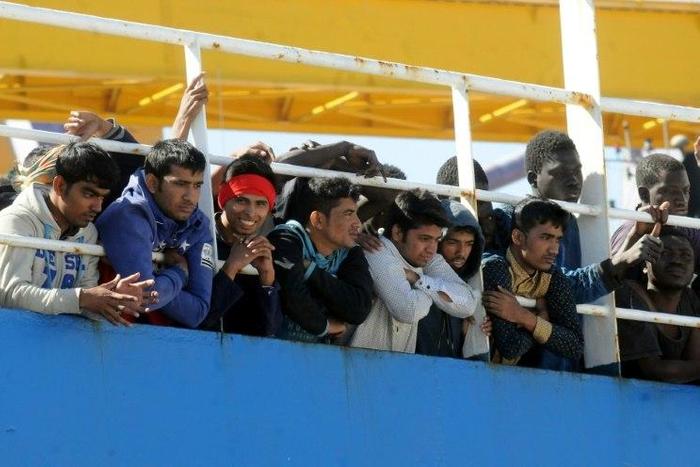 Men wait on deck of a merchant ship at their arrival along with 470 migrants and refugees after being rescued at sea off the Libyan coasts, on April 18, 2017