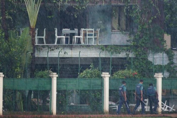 Policemen check the back garden of an upscale cafe in Dhaka on July 3, 2016 a day after a bloody siege ended with the death of 22 hostages, including 18 foreigners