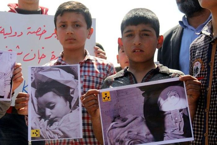Syrian residents of Khan Sheikhun hold placards and pictures on April 7, 2017 during a protest condemning a suspected chemical weapons attack on their town that killed at least 86 people