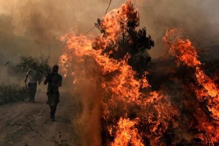Greek firefighters and volunteers trying to extinguish a fire east of Athens, as the army was called in to assist the effort