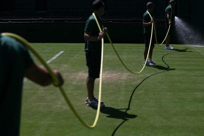 Ground staff water a tennis court at The All England Tennis Club in Wimbledon, southwest London, on July 2, 2017, on the eve of the start of the 2017 Wimbledon Championships tennis tournament