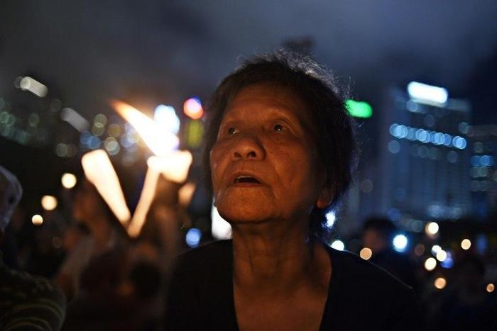 An elderly participant holds a candle with others as they attend a candlelight vigil at Hong Kong's Victoria Park on June 4, 2017, to mark the 28th anniversary of the 1989 Tiananmen crackdown in Beijing