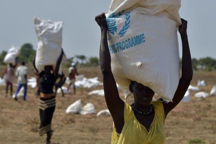 A woman carries a sack of food after a World Food Programme aid drop in South Sudan in February 2015