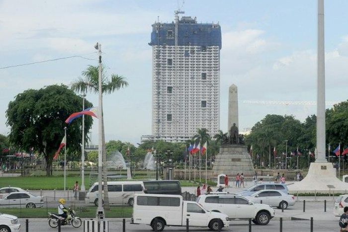 The 49-storey Torre de Manila high-rise condominium looms in the background from the Jose Rizal tomb and monument at Luneta Park in Manila