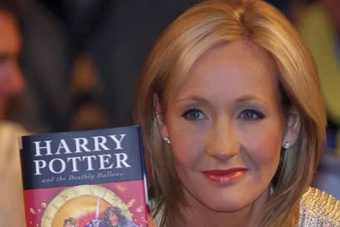 JK Rowling holding a copy of Harry Potter and the deathly hallows
