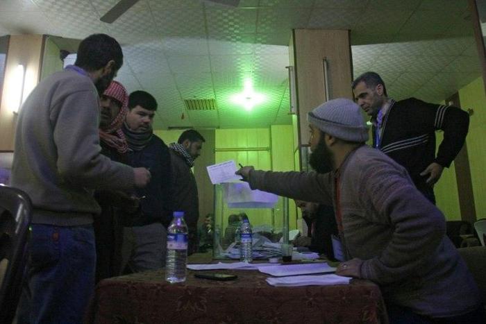 Syrian men queue to cast their vote at a polling station in the city of Idlib as they elect the city's first civilian council, two years after it was overrun by rebels and jihadists, on January 17, 2017