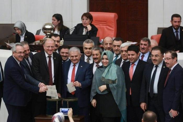Turkey's Prime Minister Binali Yildirim (C) accompanied by lawmakers vote following a parliament debate on January 21, 2017 on proposed amendments to the country's constitution