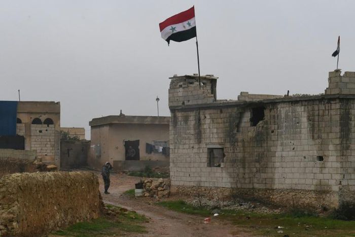 A Syrian national flag flies as regime forces gather in the countryside south of the northern Kurdish-controlled city of Manbij on December 30, 2018