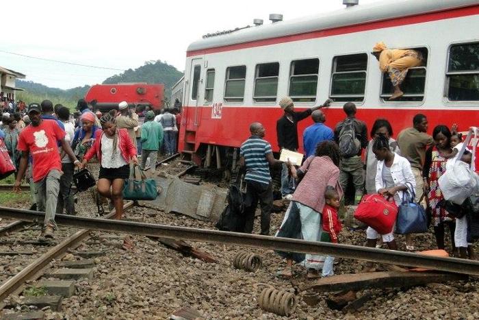 A passenger escapes a train car using a window as others leave from the site of a train derailment in Eseka on October 21, 2016