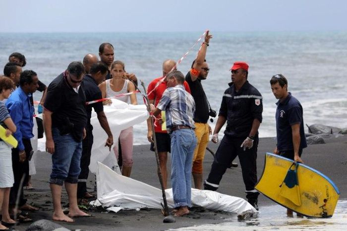 Police, firefighters and onlookers stand by the covered body of a bodyboarder killed by a shark on a beach in Saint-Andre, on the French Reunion Island in the Indian Ocean on February 21, 2017