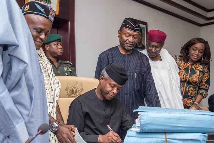 Acting President, Prof. Osinbajo signing the budget with other officials of government .