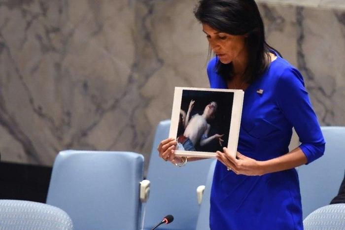 US Ambassador to the UN Nikki Haley holds photos of victims as she speaks at the UN Security Council on April 5, 2017, about the suspected deadly chemical attack that killed civilians, including children, in Syria