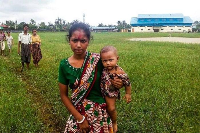 A woman holds a child in her arms as she arrives at Yathae Taung township in Rakhine state after fleeing violence in their home village