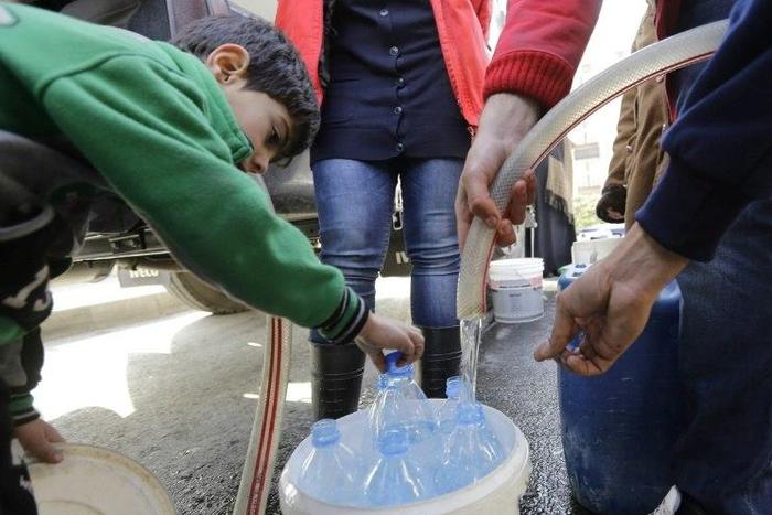 Damascus residents fill plastic containers with water provided by the Syrian Arab Red Crescent in the capital on January 10, 2017
