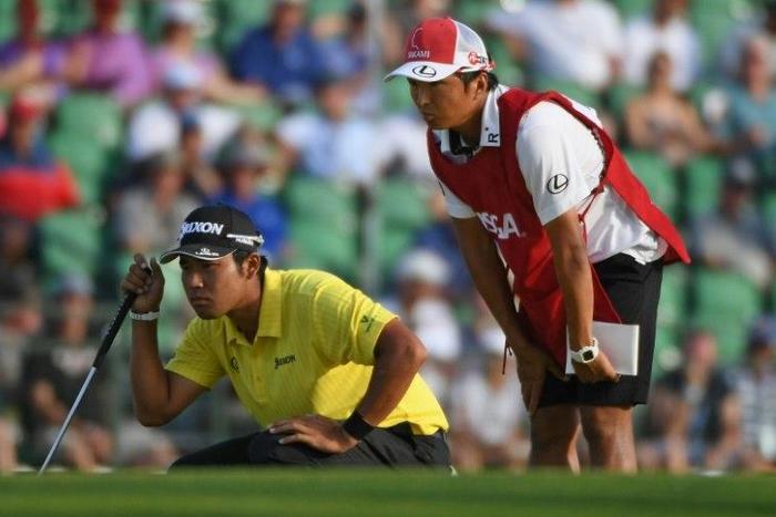 Hideki Matsuyama of Japan and caddie Daisuke Shindo line up a putt on the 18th green during the second round of the 2017 US Open, at Erin Hills in Hartford, Wisconsin, on June 16