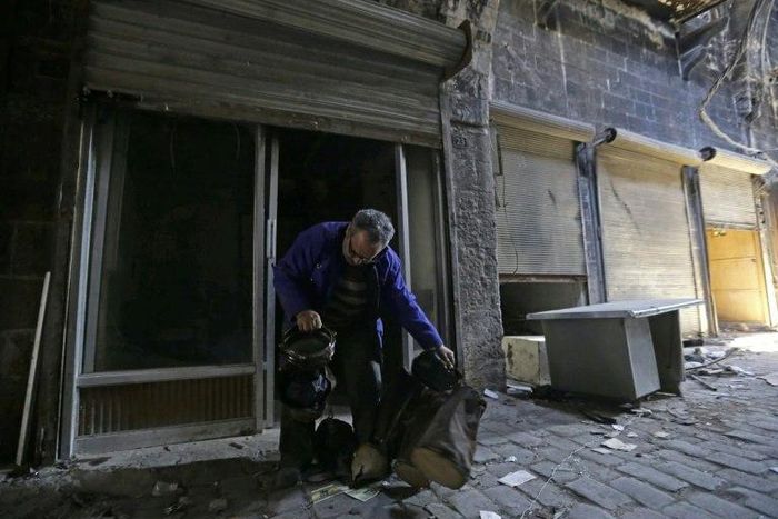 Mohammed Nour Mimi looks at a drum as he rummages through his store to find surviving musical instruments in Aleppo's historic souk