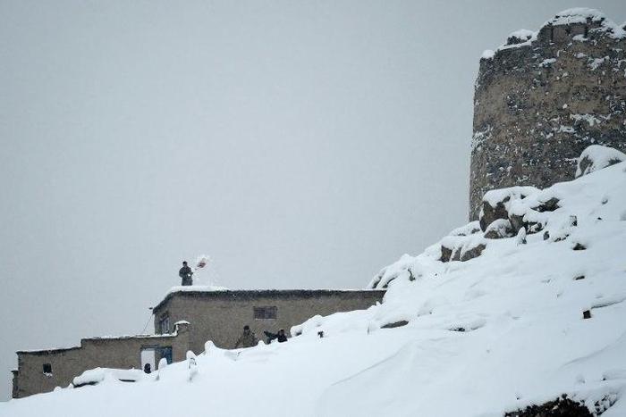 A Kabul resident shovels snow from a roof of his home after a major snowfall in the Afghan capital on February 5, 2017