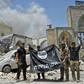 Iraqi soldiers pose with an upside-down flag of the Islamic State group outside the ruins of the Nuri mosque in the Old City of Mosul on June 30, 2017