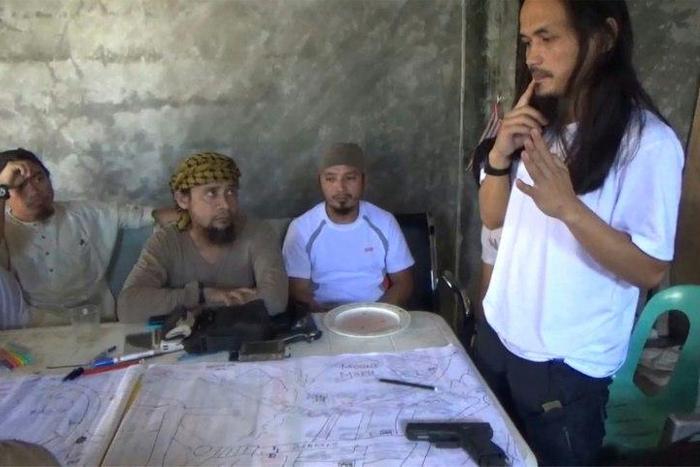 Screengrab taken from video released by the Philippine Army on June 18, 2017 shows Isnilon Hapilon (2nd L), leader of hardline group Abu Sayyaf, and Abdullah Maute (R) discussing an improvised map of Marawi at an undisclosed location on Mindanao