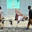 Residents carry an injured man wounded during a complex car bomb attack targeting a Mogadishu hotel on January 25, 2017