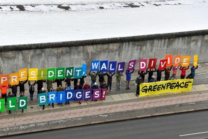 Activists from Greenpeace display a message reading "Mr President, walls divide. Build Bridges!" along the Berlin wall in Berlin on January 20, 2017 to coincide with the inauguration of Donald Trump as the 45th president of the United States