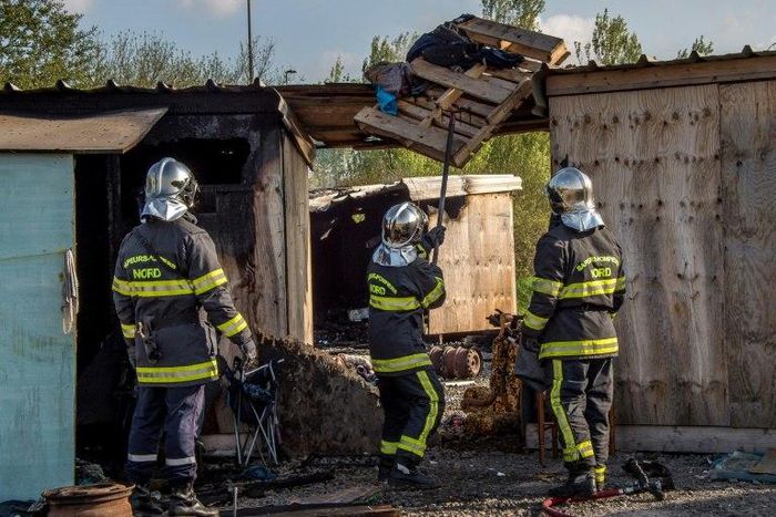French firemen inspect a burnt hut at the Grande-Synthe migrant camp on the outskirts of Dunkirk, on April 11, 2017