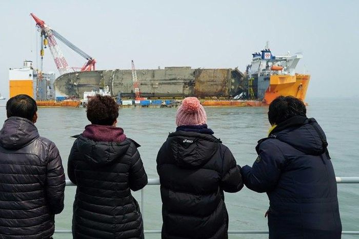 Relatives of the missing from the Sewol ferry disaster look at the damaged ferry during a memorial service from a ship off the coast of the southern South Korean island of Jindo on March 28, 2017
