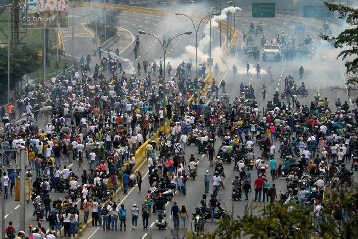 Police fired tear gas and rubber bullets to break up thousands of marchers as they reached a vital freeway in Caracas