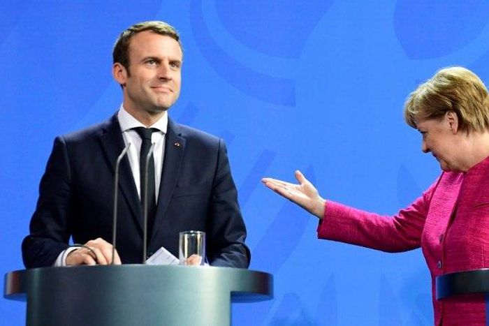 German Chancellor Angela Merkel gestures to Emmanuel Macron during a joint press conference, a day after the new French president took office