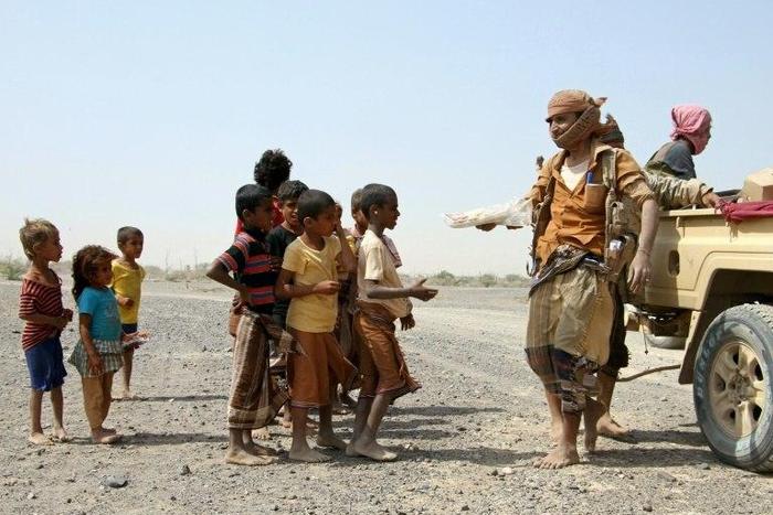 Pro-regime fighters give food to Yemeni children on the road leading to the southwestern port city of Mokha, on January 26, 2017