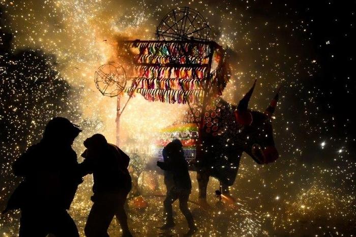 People run away from fireworks exploding around them next to a traditional "torito" (little bull) made of paper, wood and fireworks, during the San Juan de Dios festival in Tultepec, on March 8, 2017