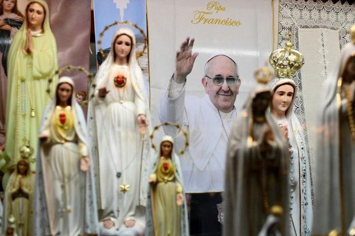 A poster depicts Pope Francis among statues of Our Lady of Fatima in a window shop of souvenirs in Fatima, central Portugal, ahead of his visit