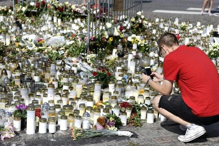 People bring candles and flowers to a makeshift memorial for the victims of the stabbings in the Finnish city of Turku