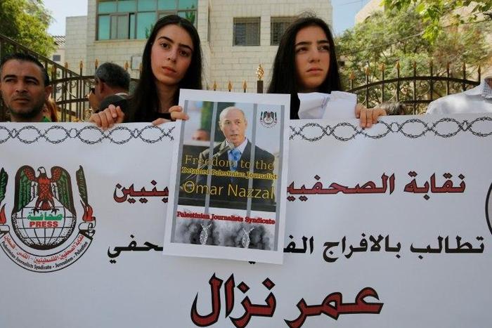 Palestinian journalists hold placards during a demonstration on April 24, 2016, outside the Red Cross offices in the West Bank city of Ramallah, in support of their colleague, Omar Nazzal, who was detained the previous day by Israeli forces