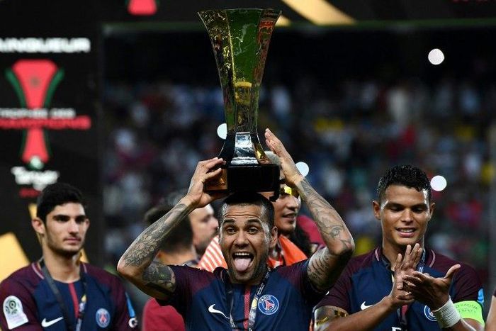 Paris Saint-Germain's defender Dani Alves holds the trophy as he celebrates with teammates after winning the French Trophy of Champions on July 29, 2017