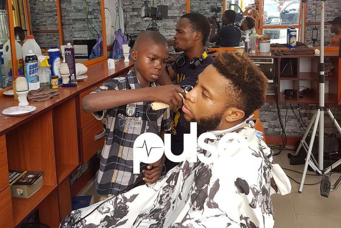 Lekan giving Pulse Tv's Chuey a haircut while Chris records them.