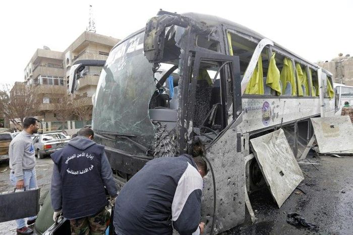 Syrian forensics experts examine a damaged bus following bomb attacks in Damascus' Old City on March 11, 2017
