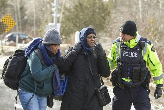 An RCMP officer speaks with women from Sudan after they illegally crossed the Canada-US border near Hemmingford, Quebec