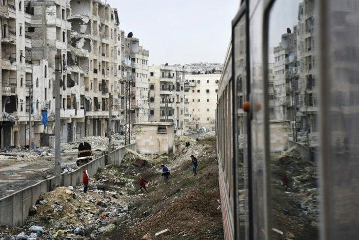 Syrian children look at a train travelling through Aleppo's devastated eastern districts for the first time in more than four years