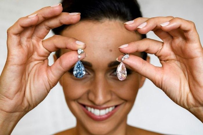 A model poses with the "The Apollo Blue" and "The Artemis Pink" diamonds, mounted as earrings, sold for a collective $57.4-million