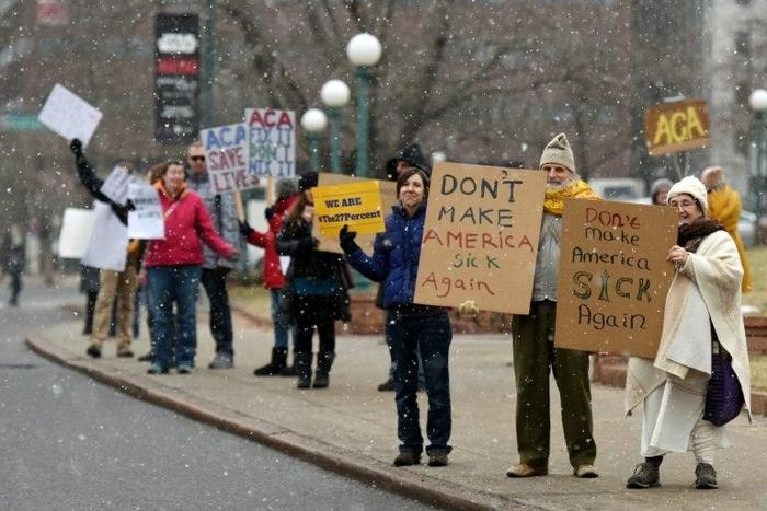 Demonstartors hold signs in the snow during a rally in support of the Affordable Care Act (ACA) in Denver, Colorado on January 15, 2017