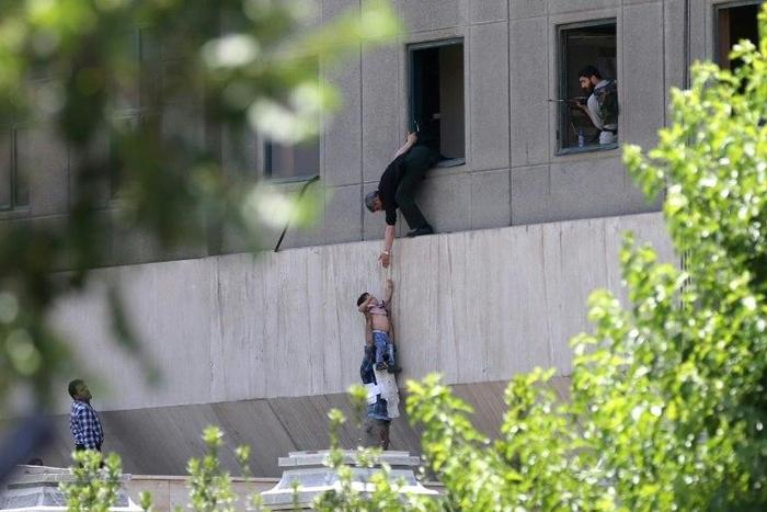 Iranian policemen evacuate a child from the parliament building in Tehran on June 7, 2017 during an attack on the complex