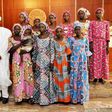 Nigerian President Muhammadu Buhari (C) poses at State House in Abuja on October 19, 2016 with the 21 Chibok girls who were released by Boko Haram the previous week