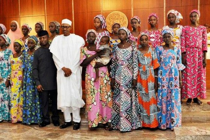 Nigerian President Muhammadu Buhari (C) poses at State House in Abuja on October 19, 2016 with the 21 Chibok girls who were released by Boko Haram the previous week