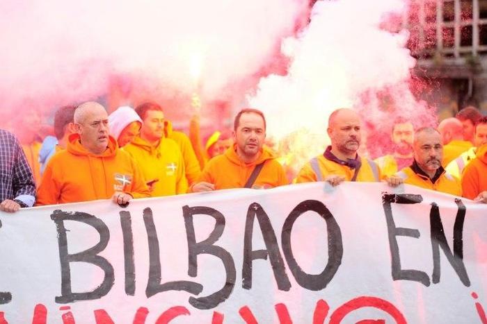 Bilbao's dockers hold a banner with flares in background during a two-day strike at the Port of Bilbao, in the Spanish Basque city of Santurtzi on June 15, 2017