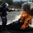 A policeman tries to extinguish a fire after demonstrators burnt tyres to barricade a road during violent protests in Ennerdale