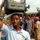 A man makes his protest by holding a generator set on his head.
